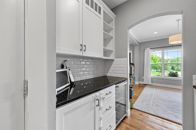 917 Robin Rd, Iowa City, IA 52246 - kitchen featuring wine cooler, light wood finished floors, white cabinetry, decorative backsplash, and arched walkways