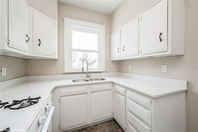 kitchen featuring white cabinetry, white gas stove, light countertops, and a sink