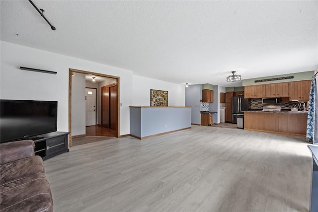 3325 29th Ave, Marion, IA 52302 - unfurnished living room featuring baseboards, a sink, light wood-type flooring, and a textured ceiling