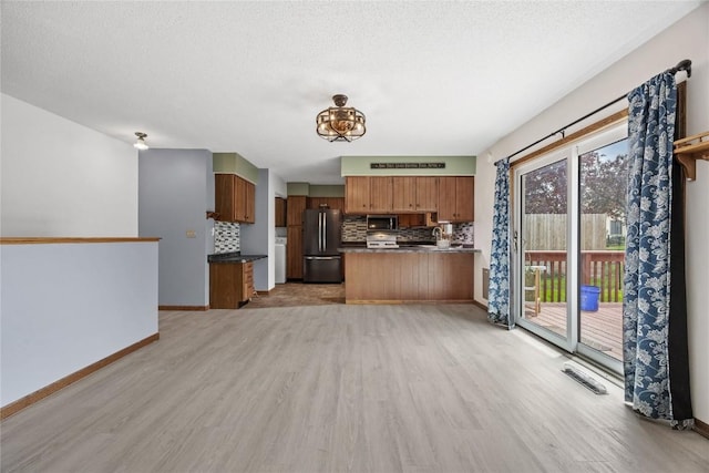 3325 29th Ave, Marion, IA 52302 - kitchen featuring light wood finished floors, a peninsula, brown cabinets, tasteful backsplash, and appliances with stainless steel finishes