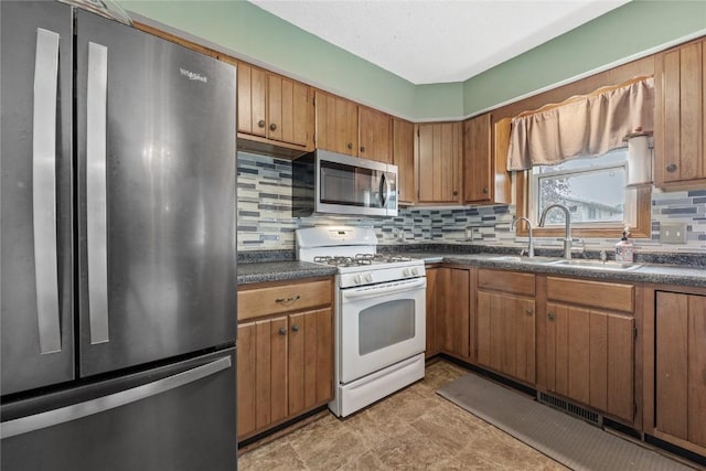 3325 29th Ave, Marion, IA 52302 - kitchen featuring dark countertops, tasteful backsplash, appliances with stainless steel finishes, and a sink