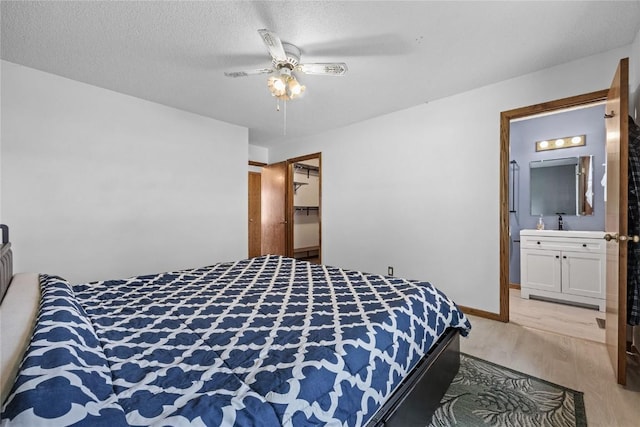 3325 29th Ave, Marion, IA 52302 - bedroom featuring light wood finished floors, connected bathroom, a sink, baseboards, and ceiling fan