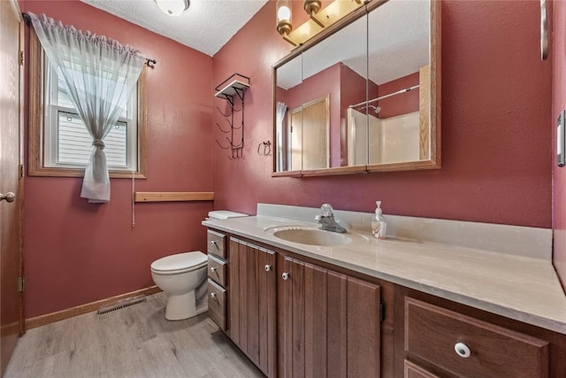 3325 29th Ave, Marion, IA 52302 - full bathroom with toilet, wood finished floors, vanity, a textured ceiling, and visible vents