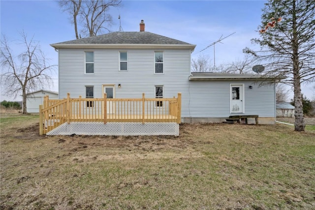 rear view of property featuring a chimney, a lawn, a shingled roof, entry steps, and a wooden deck
