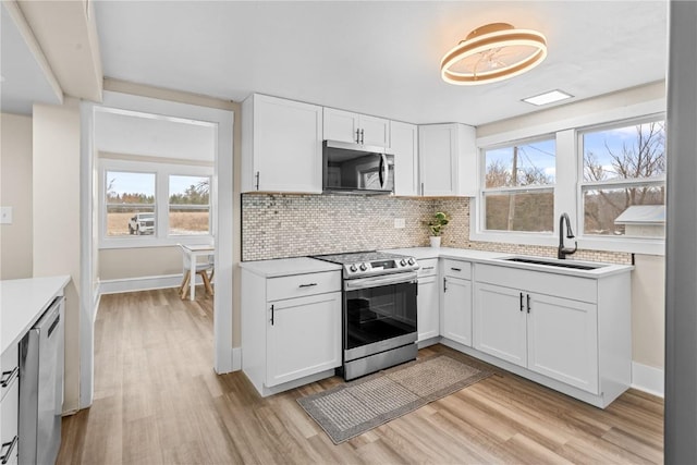 kitchen featuring light wood-style floors, light countertops, appliances with stainless steel finishes, and a sink