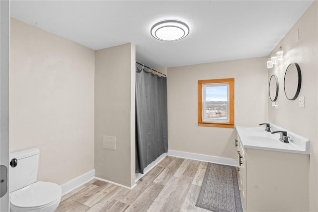 bathroom with toilet, wood finished floors, vanity, a shower with shower curtain, and baseboards