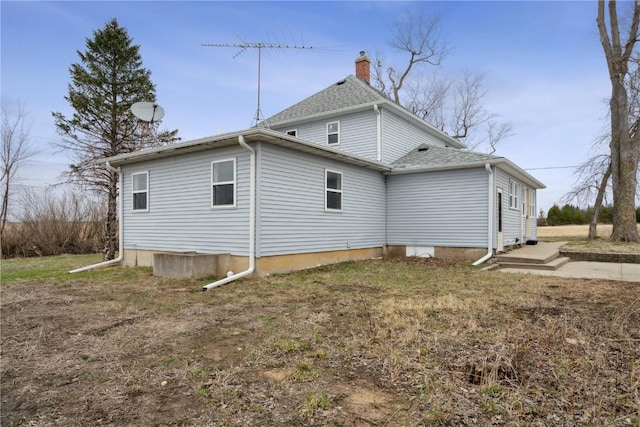 view of side of property with a chimney and a shingled roof