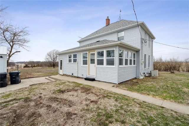 rear view of house featuring a chimney, entry steps, a patio area, and roof with shingles