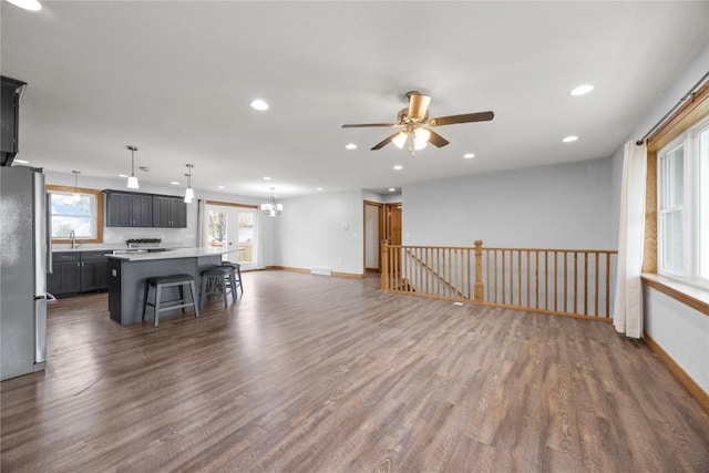 unfurnished living room with visible vents, recessed lighting, dark wood-style floors, and ceiling fan with notable chandelier