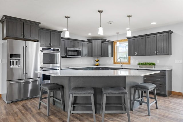 kitchen featuring a sink, a breakfast bar, stainless steel appliances, dark wood finished floors, and light countertops