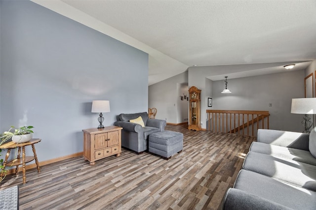 living area with baseboards, vaulted ceiling, and wood finished floors