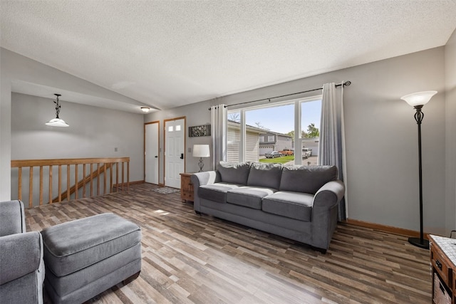 living area with lofted ceiling, a textured ceiling, baseboards, and wood finished floors