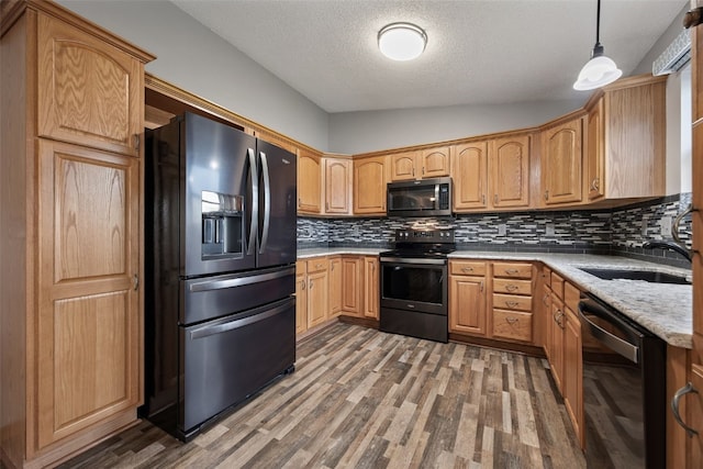 kitchen featuring a sink, wood finished floors, a textured ceiling, black appliances, and decorative backsplash