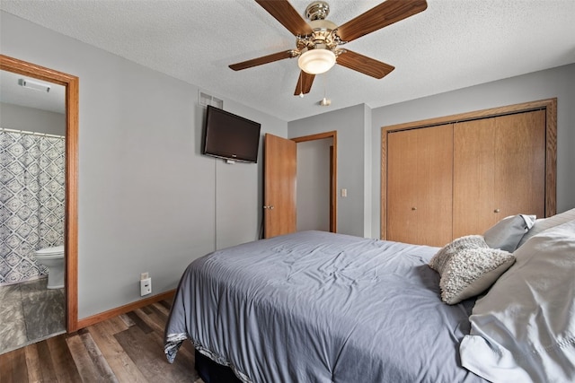 bedroom with wood finished floors, a closet, visible vents, ceiling fan, and ensuite bath