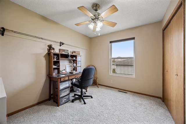 office space with a textured ceiling, light carpet, and baseboards