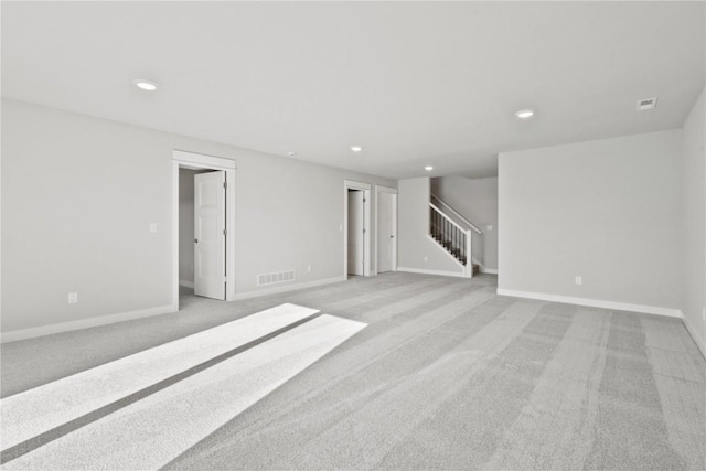 interior space featuring light colored carpet, visible vents, and stairs