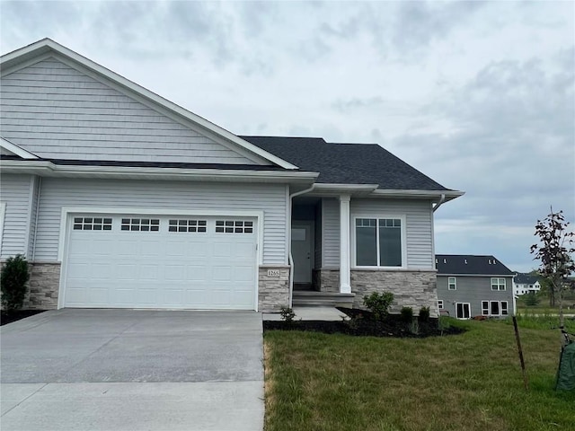 view of front of home featuring stone siding, a garage, a shingled roof, a front lawn, and driveway