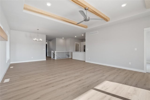 unfurnished living room with wood finished floors, ceiling fan with notable chandelier, beam ceiling, visible vents, and baseboards