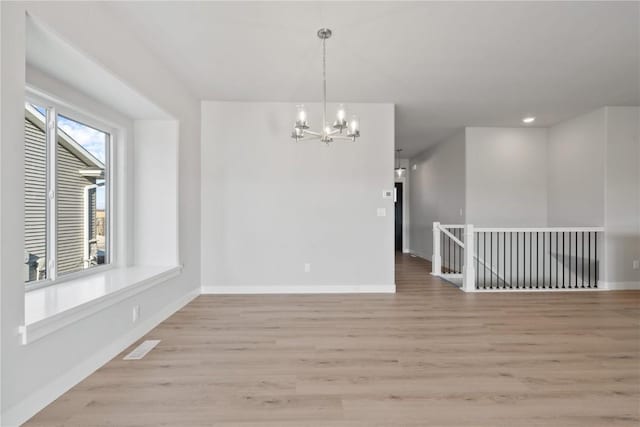 interior space featuring baseboards, a chandelier, and light wood-type flooring