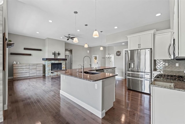 4332 Quail Trail Dr, Marion, IA 52302 - kitchen featuring appliances with stainless steel finishes, a stone fireplace, a sink, dark wood-style flooring, and backsplash