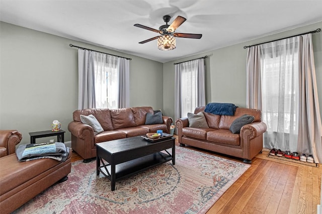 living area featuring hardwood / wood-style flooring, a wealth of natural light, and a ceiling fan