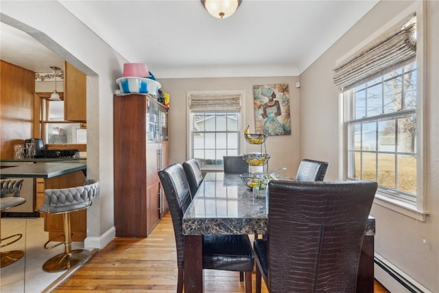 dining area featuring baseboards, a baseboard radiator, and light wood-type flooring