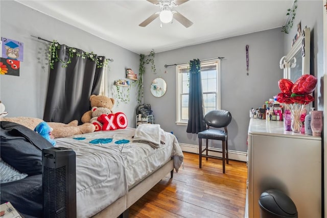 bedroom with hardwood / wood-style floors, a ceiling fan, and a baseboard heating unit