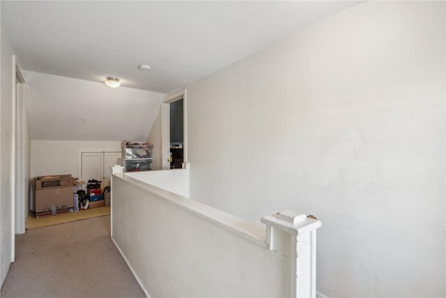 hallway with light colored carpet, lofted ceiling, and an upstairs landing