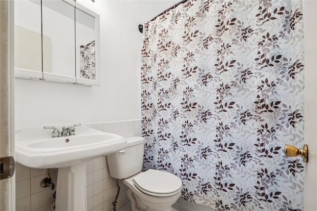 bathroom with toilet, tile walls, and wainscoting