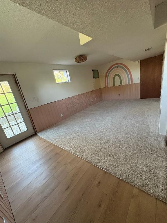 22101 Pleasant Dr, Bernard, IA 52032 - empty room featuring a wainscoted wall, wood finished floors, wooden walls, and a textured ceiling