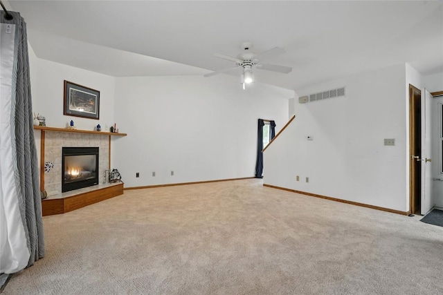 unfurnished living room featuring a ceiling fan, baseboards, visible vents, a tile fireplace, and carpet floors