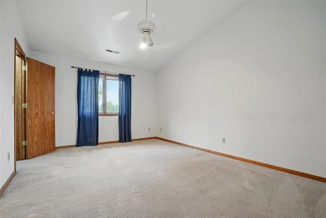 unfurnished room with vaulted ceiling, light colored carpet, baseboards, and visible vents