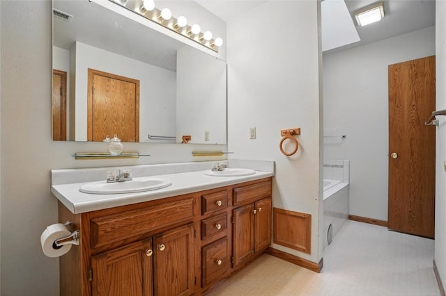 bathroom with a bath, visible vents, double vanity, and a sink