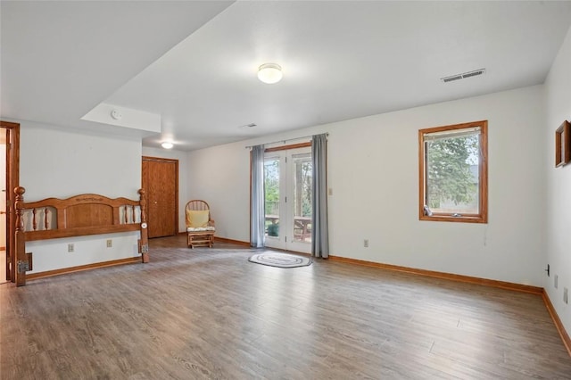 unfurnished bedroom featuring wood finished floors, baseboards, visible vents, and access to exterior