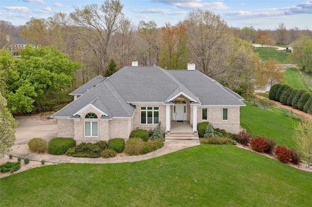 ranch-style home with a chimney, brick siding, and a front lawn