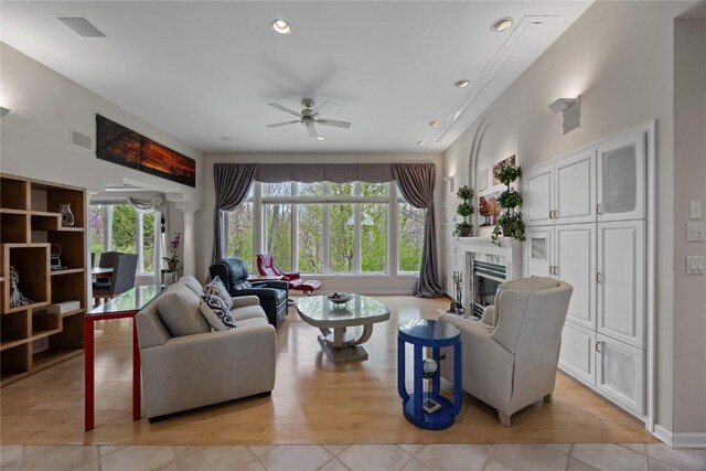 living area featuring ceiling fan, a high end fireplace, light tile patterned floors, and visible vents