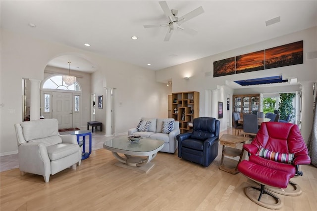 living area featuring light wood-style flooring, arched walkways, plenty of natural light, and decorative columns