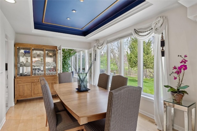 dining space with a tray ceiling, light wood-style floors, visible vents, and recessed lighting