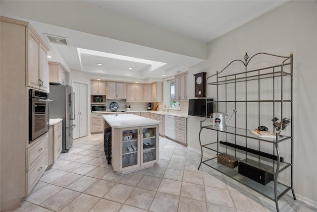 kitchen with a sink, stainless steel appliances, light tile patterned flooring, light countertops, and a raised ceiling