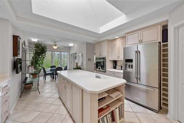 kitchen with a tray ceiling, appliances with stainless steel finishes, light tile patterned floors, and a sink