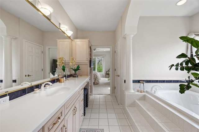 ensuite bathroom featuring vanity, tile patterned floors, a bath, and decorative columns