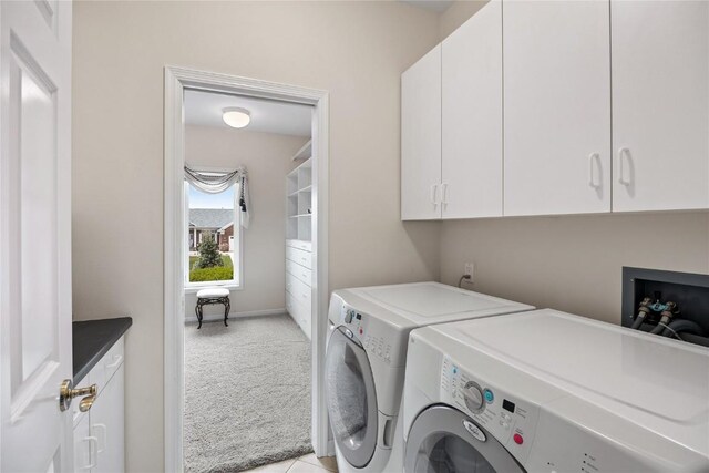 washroom featuring baseboards, light carpet, separate washer and dryer, and cabinet space