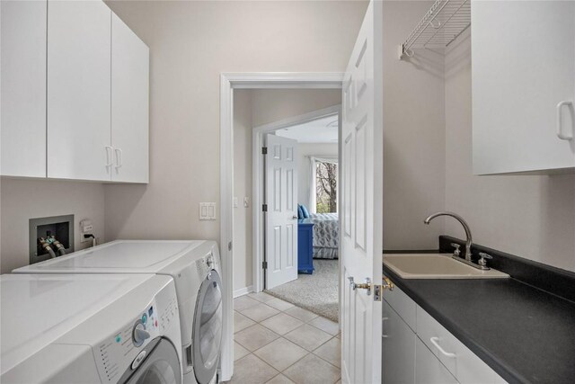 washroom featuring washing machine and dryer, light tile patterned floors, baseboards, a sink, and cabinet space