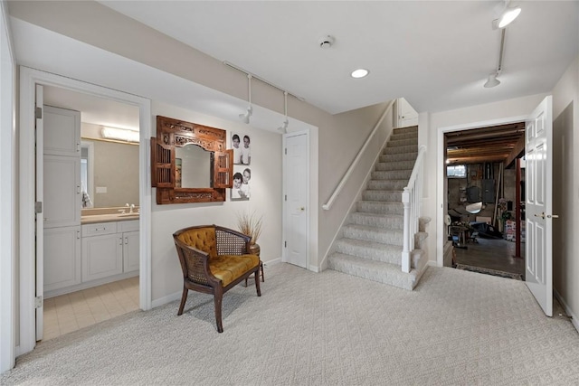sitting room featuring baseboards, stairway, and light colored carpet