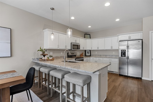kitchen with a sink, a peninsula, dark wood-type flooring, white cabinets, and appliances with stainless steel finishes