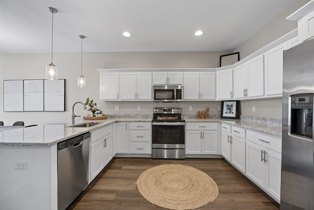 kitchen featuring decorative light fixtures, a sink, white cabinetry, a peninsula, and stainless steel appliances