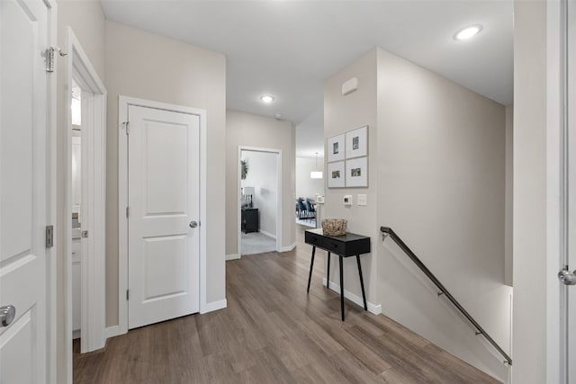 corridor featuring recessed lighting, baseboards, an upstairs landing, and wood finished floors