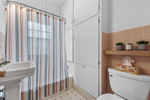 bathroom with tile walls, toilet, and shower / tub combo