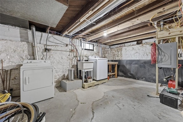 basement with electric panel, washer and clothes dryer, and a sink