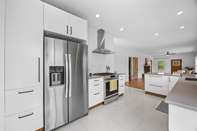 kitchen featuring recessed lighting, modern cabinets, white cabinetry, wall chimney range hood, and appliances with stainless steel finishes